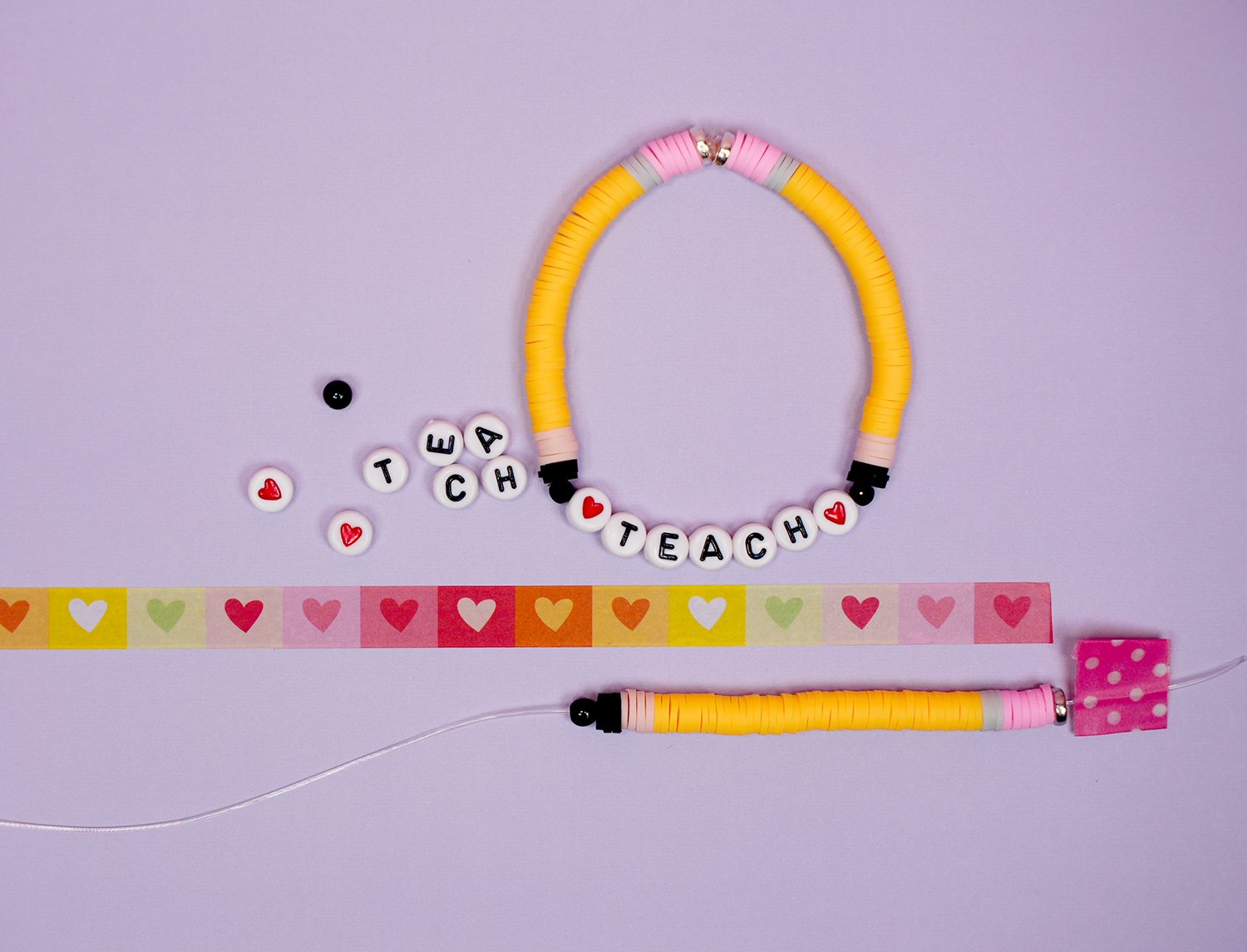 Clay bead bracelet in the making - beaded pencil on purple background with loose beads and washi tape