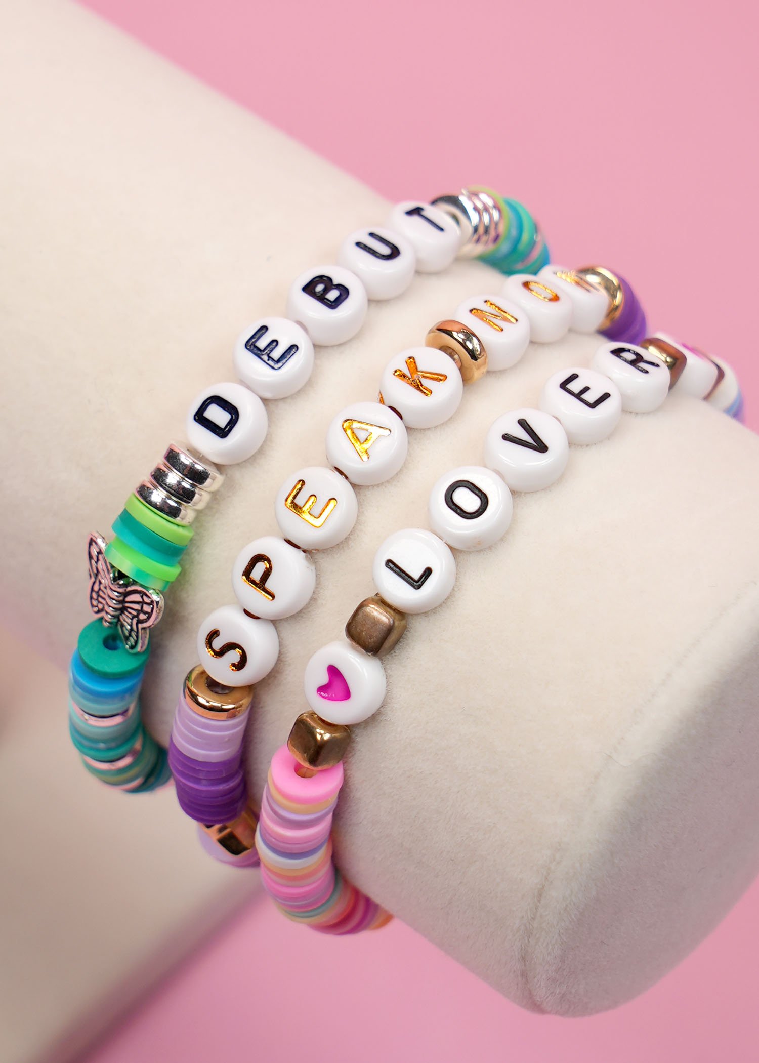 Close up view of three beaded friendship bracelets featuring Taylor Swift album names