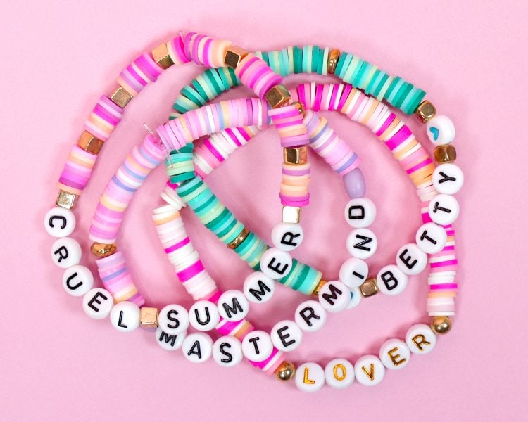 Taylor Swift friendship bracelets with Eras Tour setlist song titles on pink background