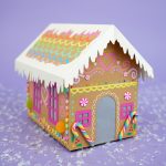 Cardboard gingerbread house with rainbow icing decorations and faux candy