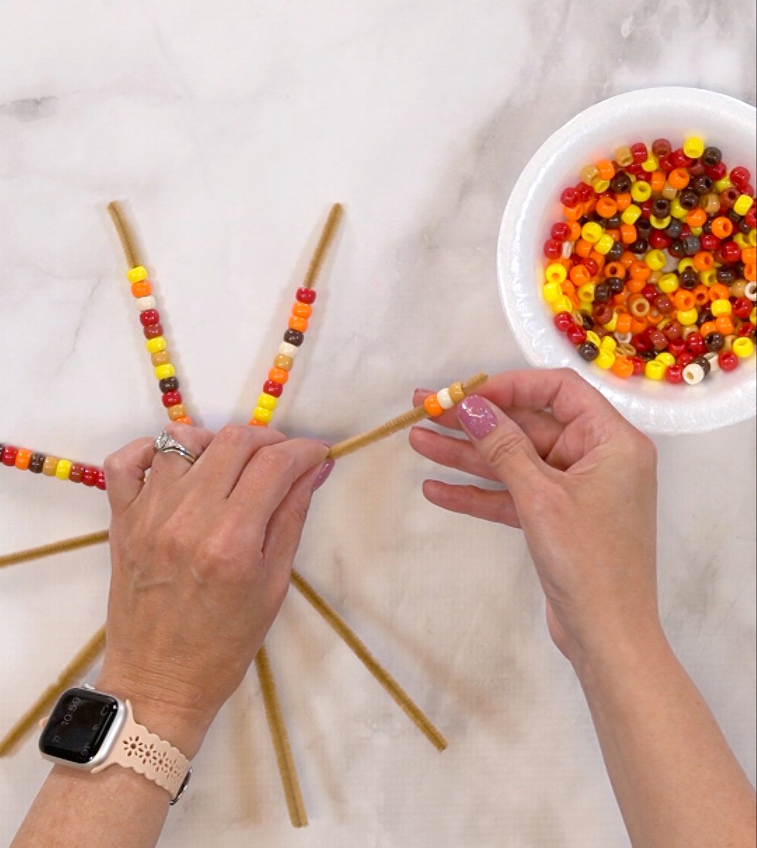 placing pony beads onto each pipe cleaner