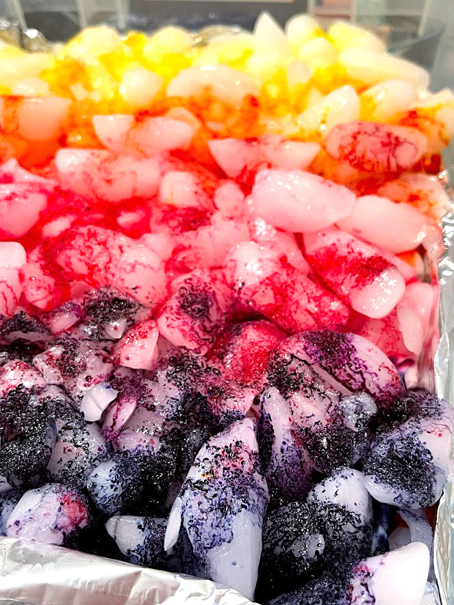 purple, pink, orange, and yellow dye on top of a pile of ice for ice dyeing