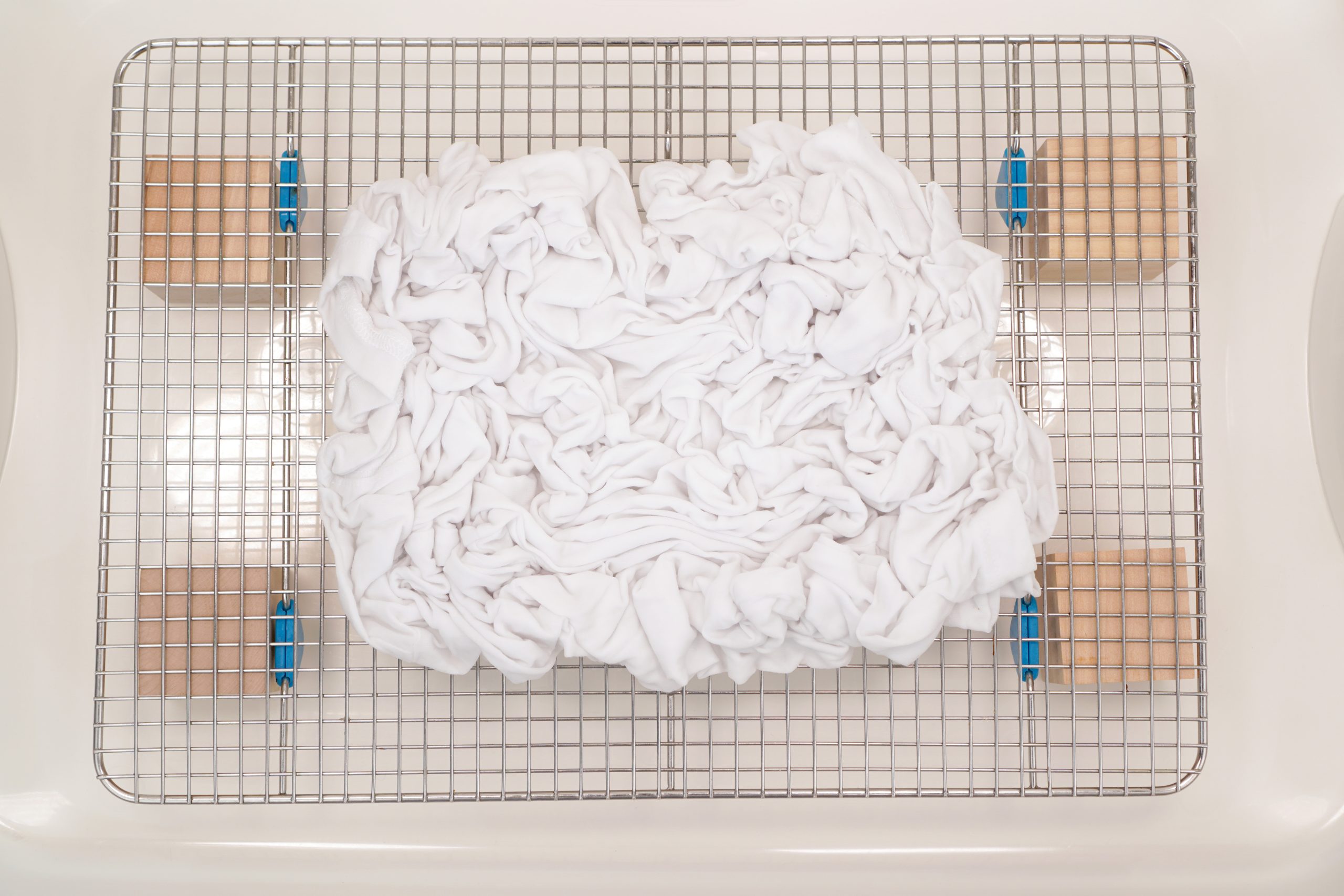 crumpled fabric atop a wire rack in bottom of plastic tub in preparation for ice dye
