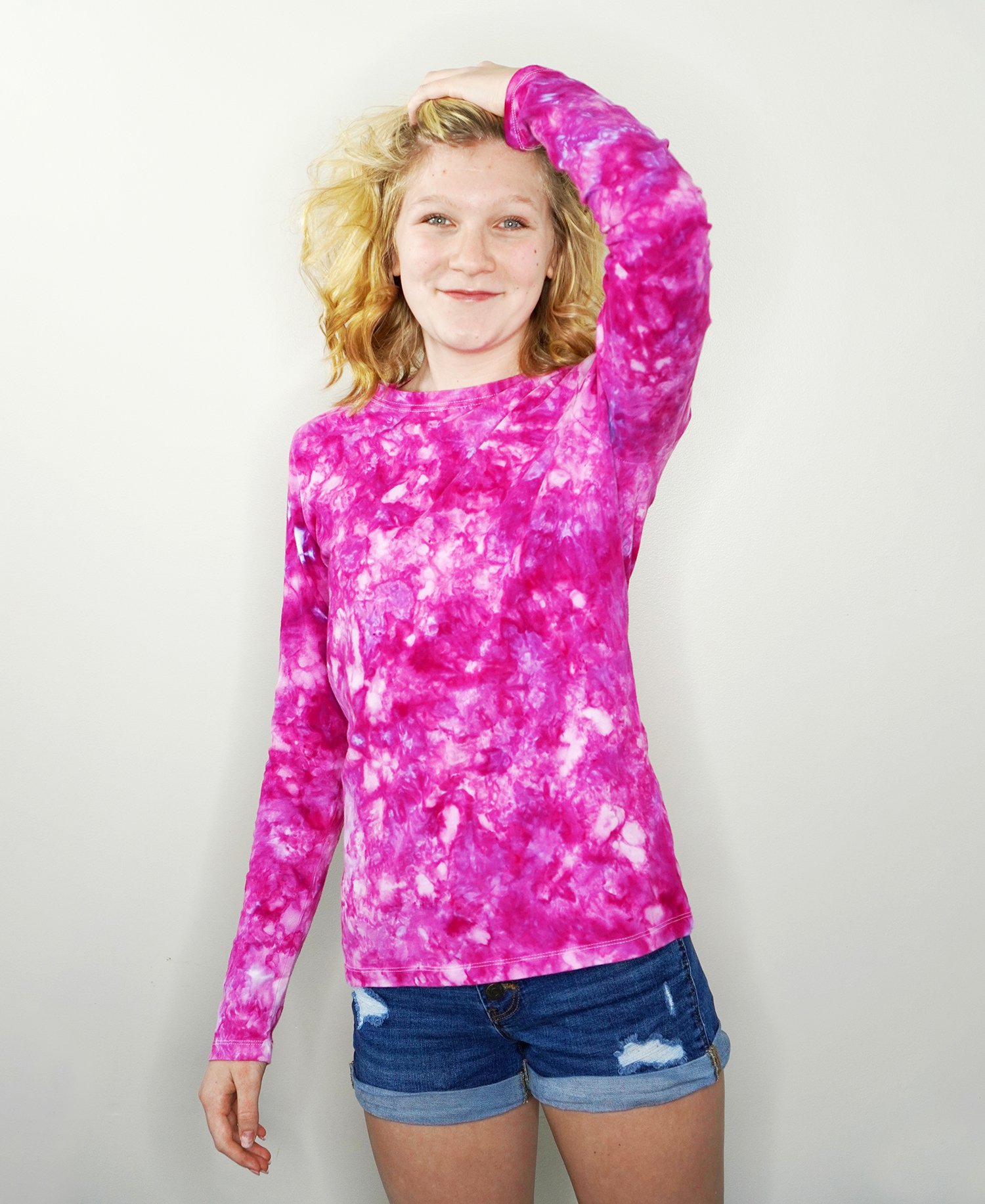 Blonde teen girl wearing a pink and purple ice dyed long sleeved shirt and denim shorts