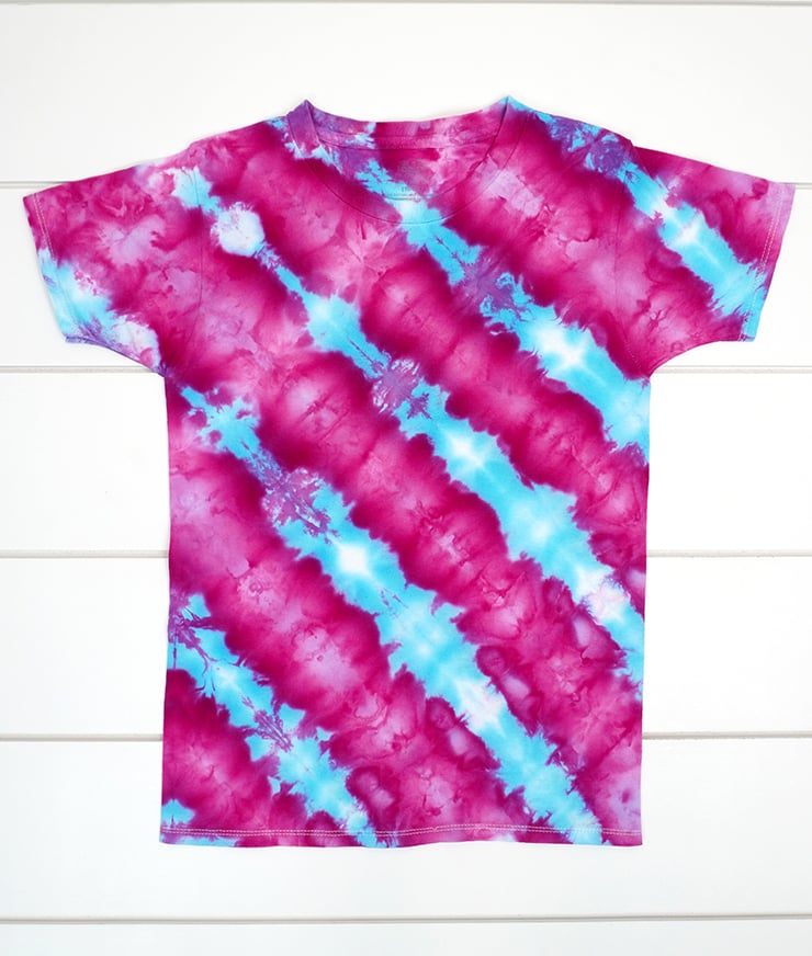 Blue and magenta diagonal striped ice dye shirt on white wood background