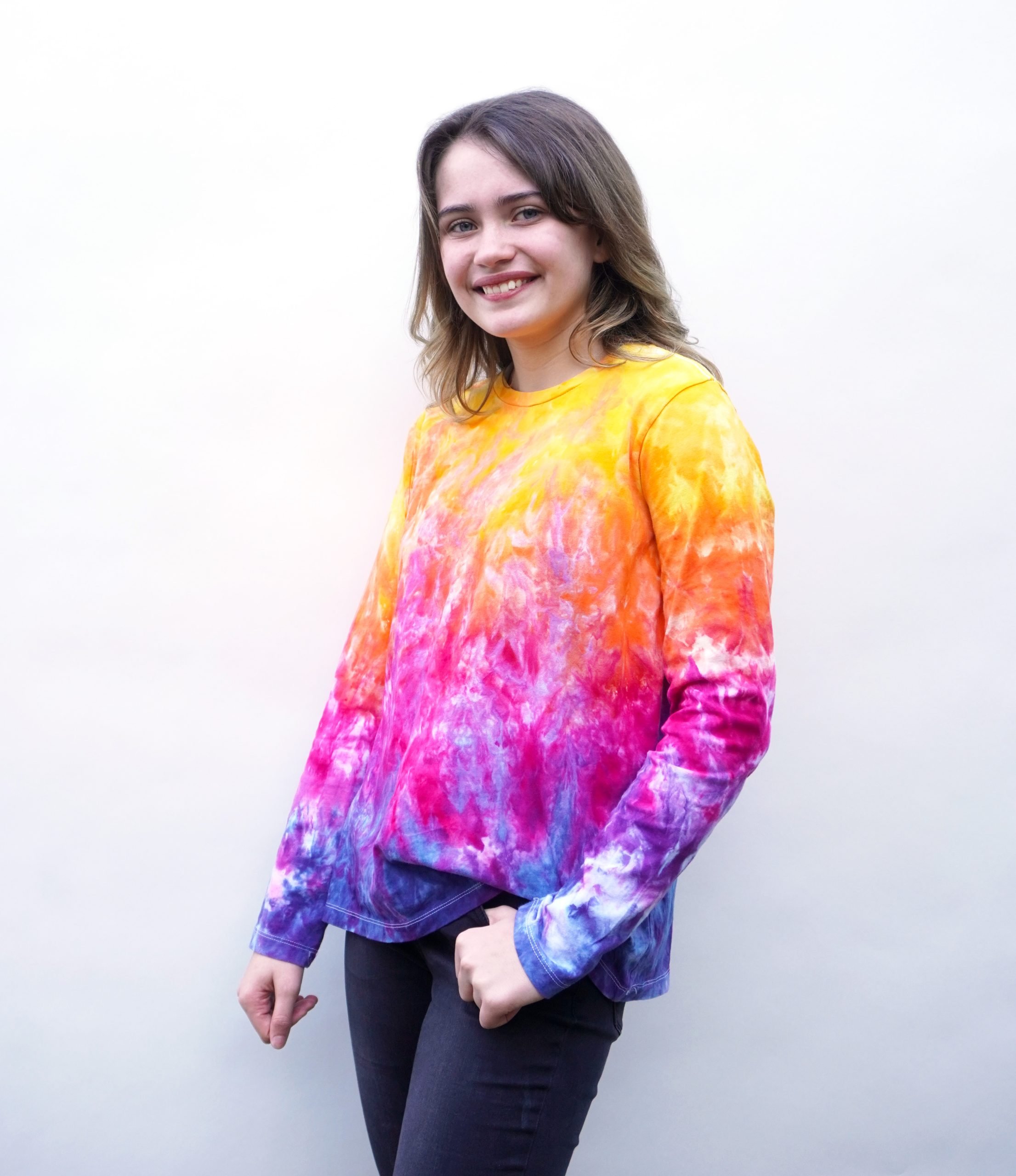 Teen girl wearing an ice-dyed tie dye shirt in rainbow sunset colors