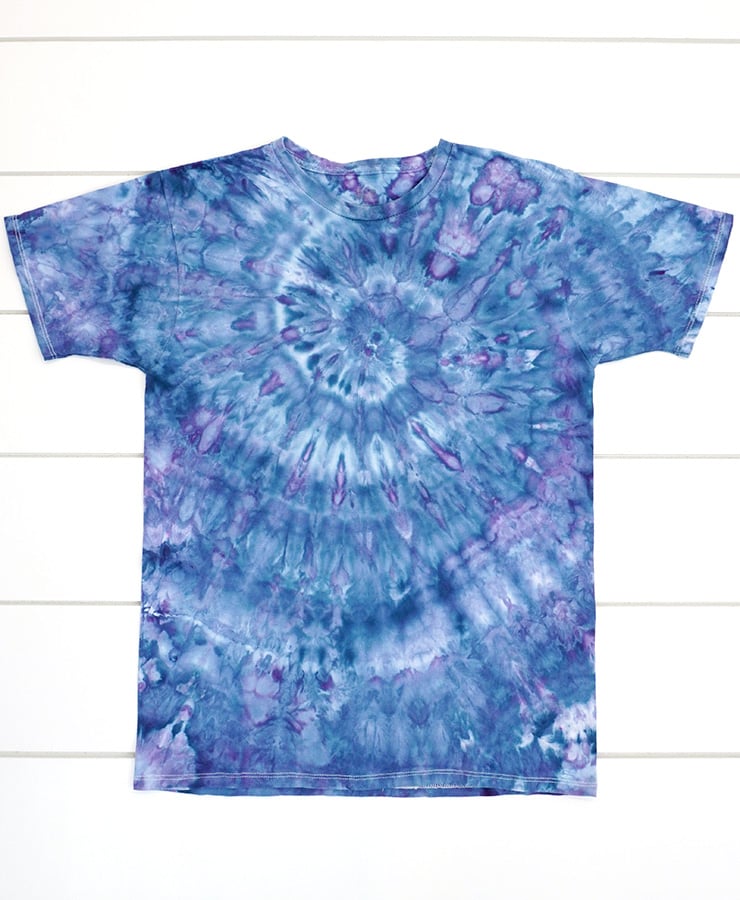 Ice dyed spiral shirt in shade of blue and purple on a white wood background