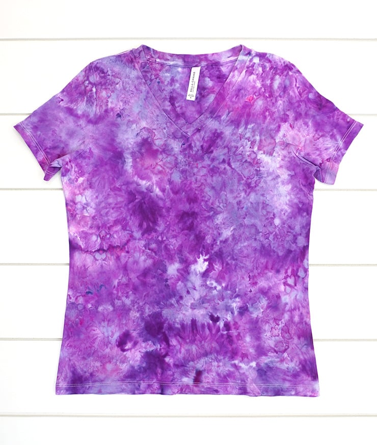 Ice dye womens v-neck t-shirt in shades of purple on white wood background