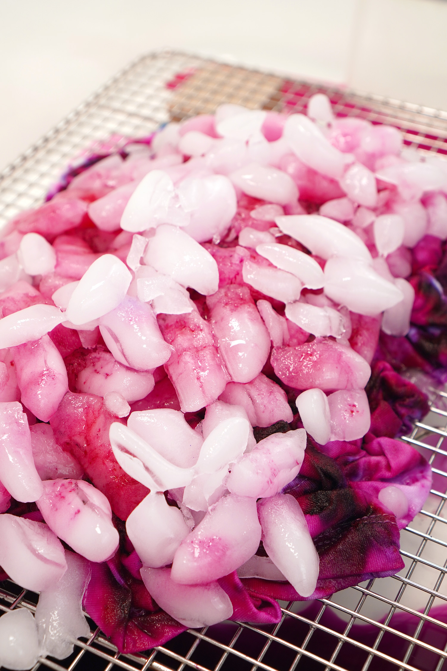 Close up of partially melted ice on top of an ice dyed pink and purple shirt