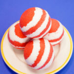 red and white striped bath bombs on white plate on blue background