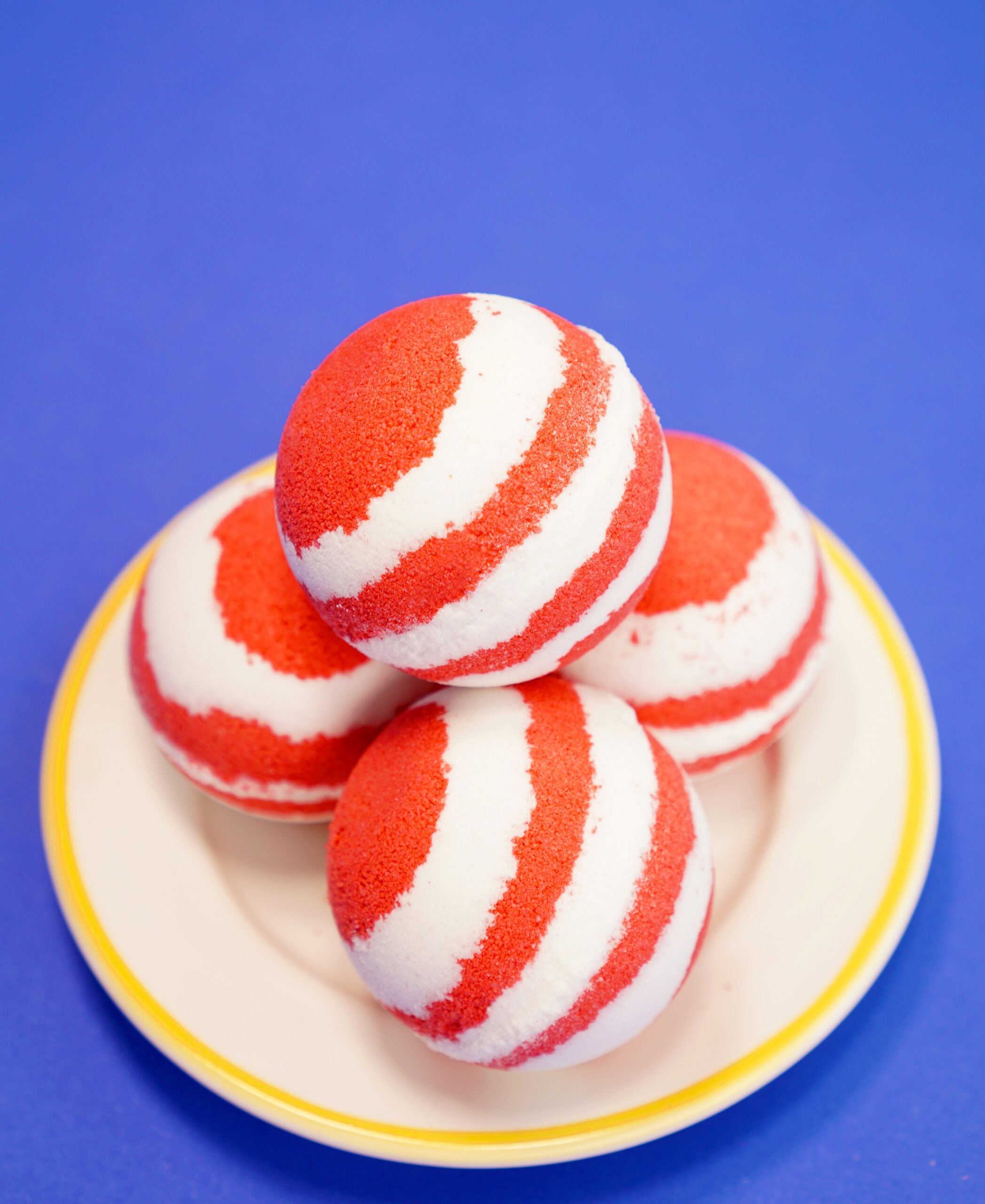 red and white striped bath bombs on white plate on blue background