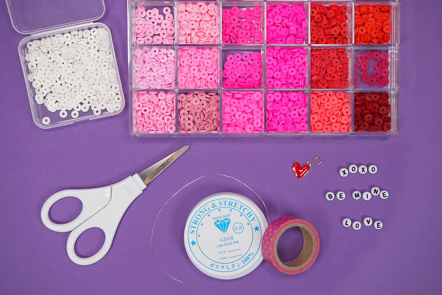 Supplies for beaded Valentine's Day bracelets on purple background - beads, scissors, string, etc.