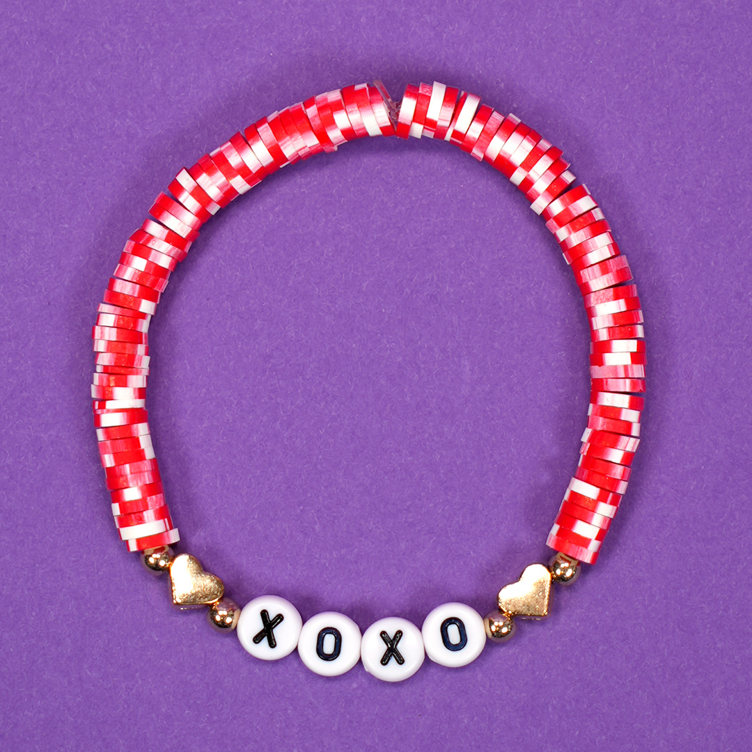 Red and white beaded Valentine's Day bracelet with XOXO heart design on purple