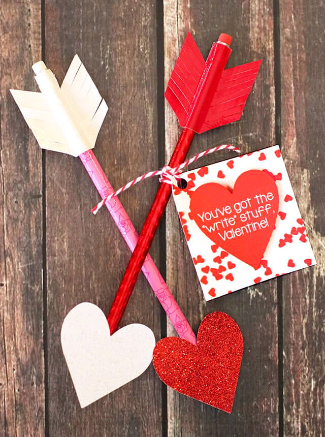 Two heart-tipped arrows made from pencils and colored tape with Valentine card