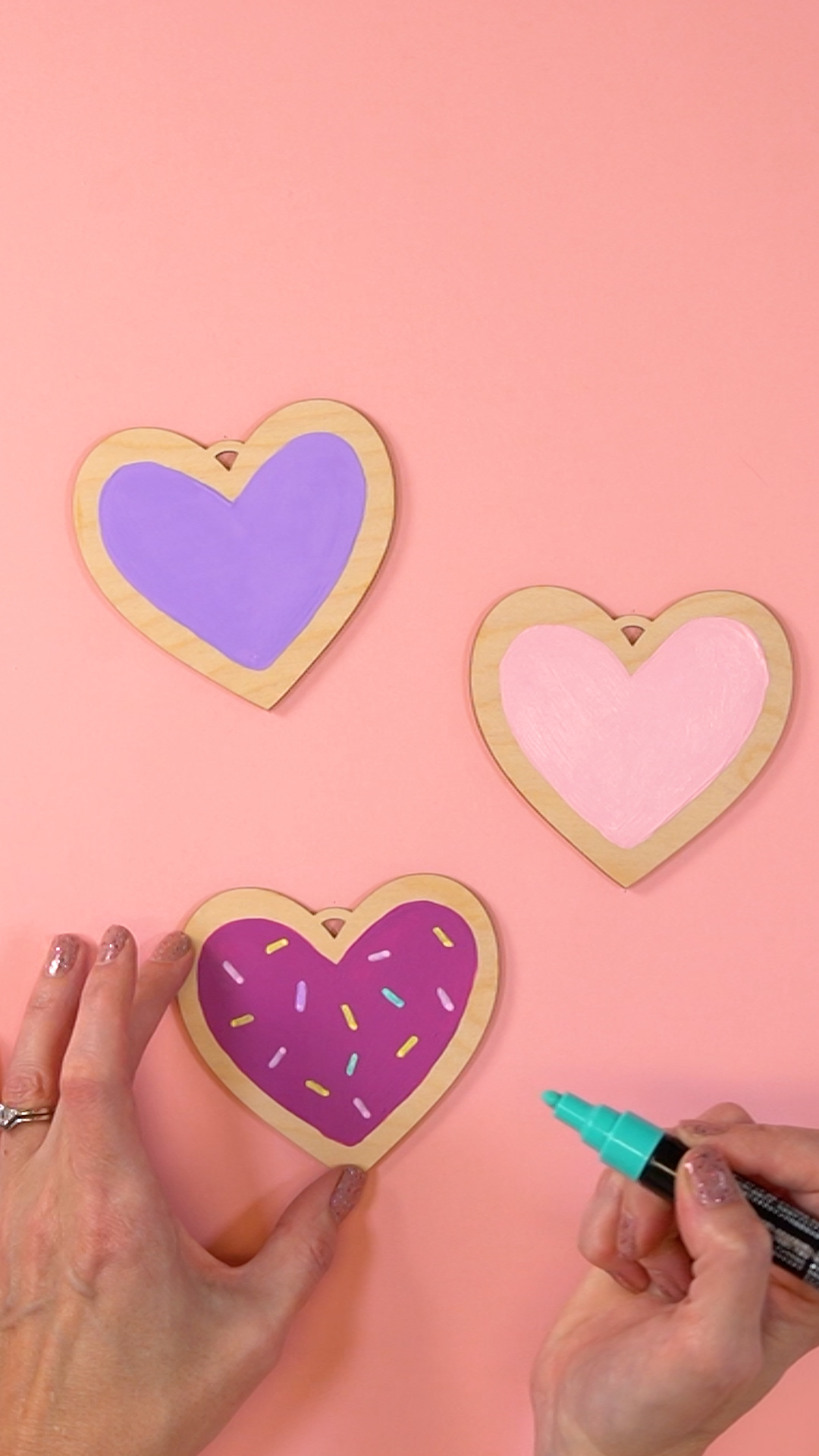 Hands with paint marker painting a Valentine's Day ornament