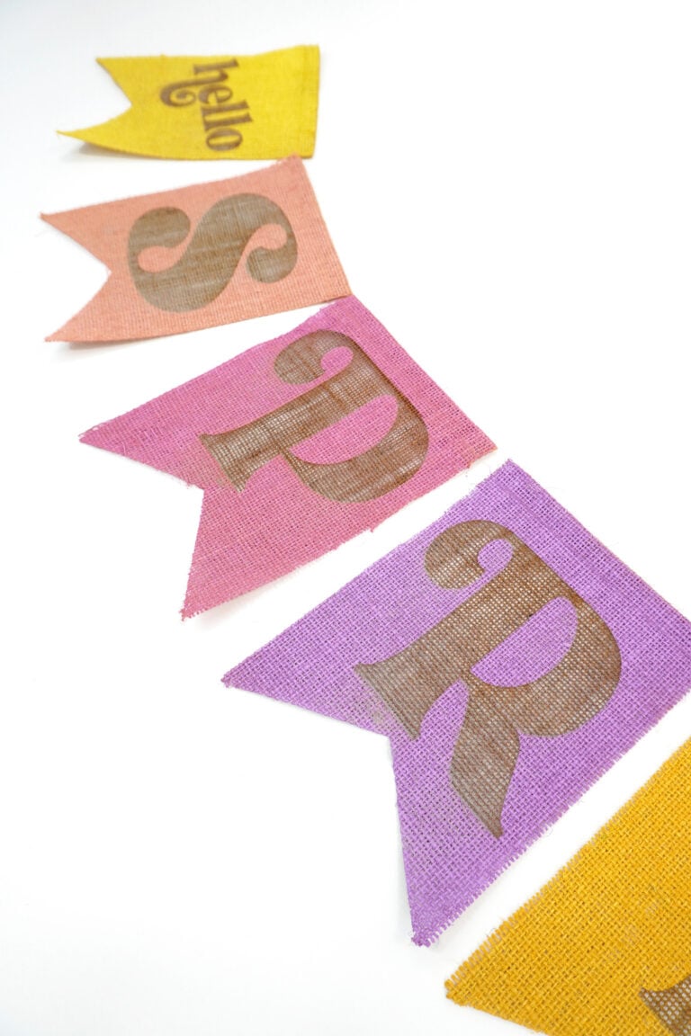 Close up of colorful "Hello Spring" laser engraved burlap banner pieces on a white background