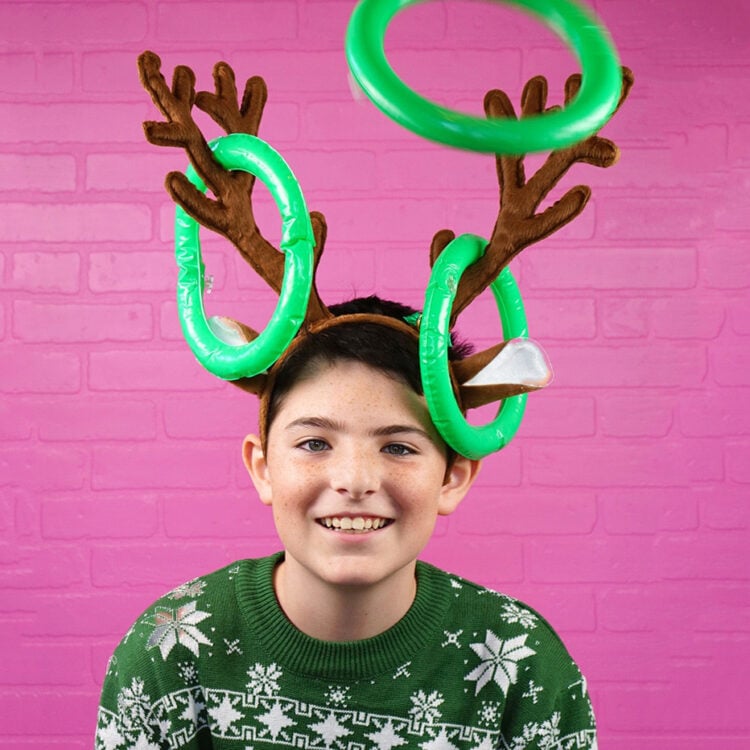 Boy wearing antler headband playing a game of ring toss for Christmas