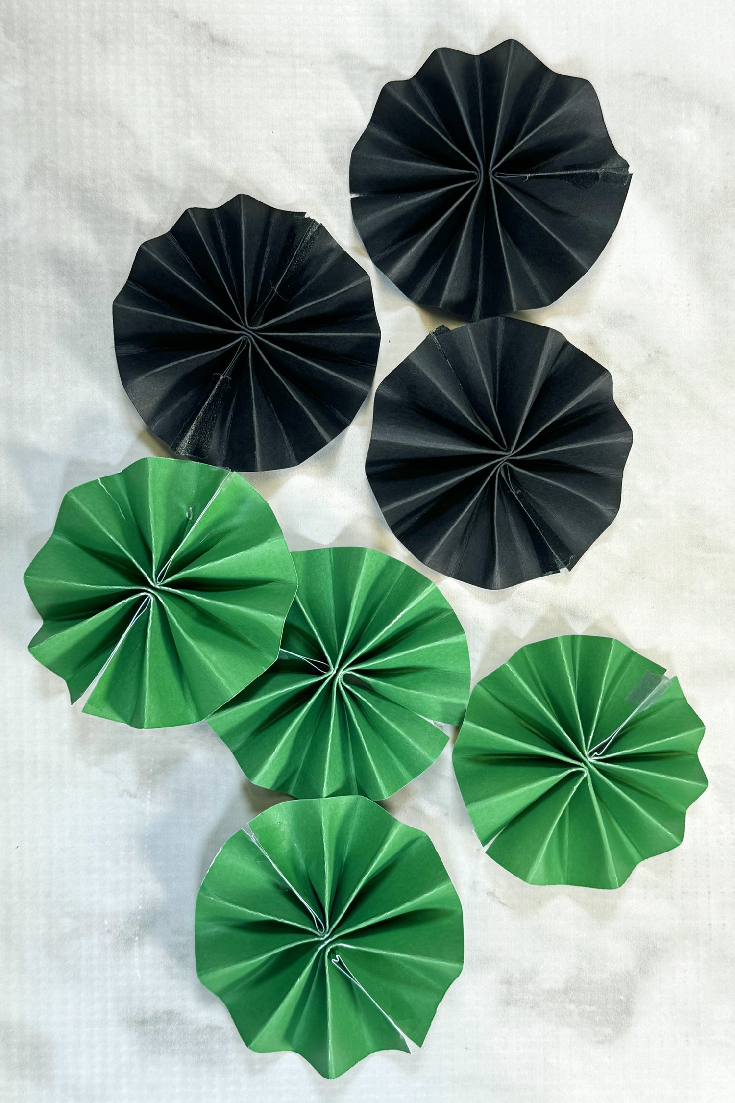 green and black paper rosettes on a grey marble background
