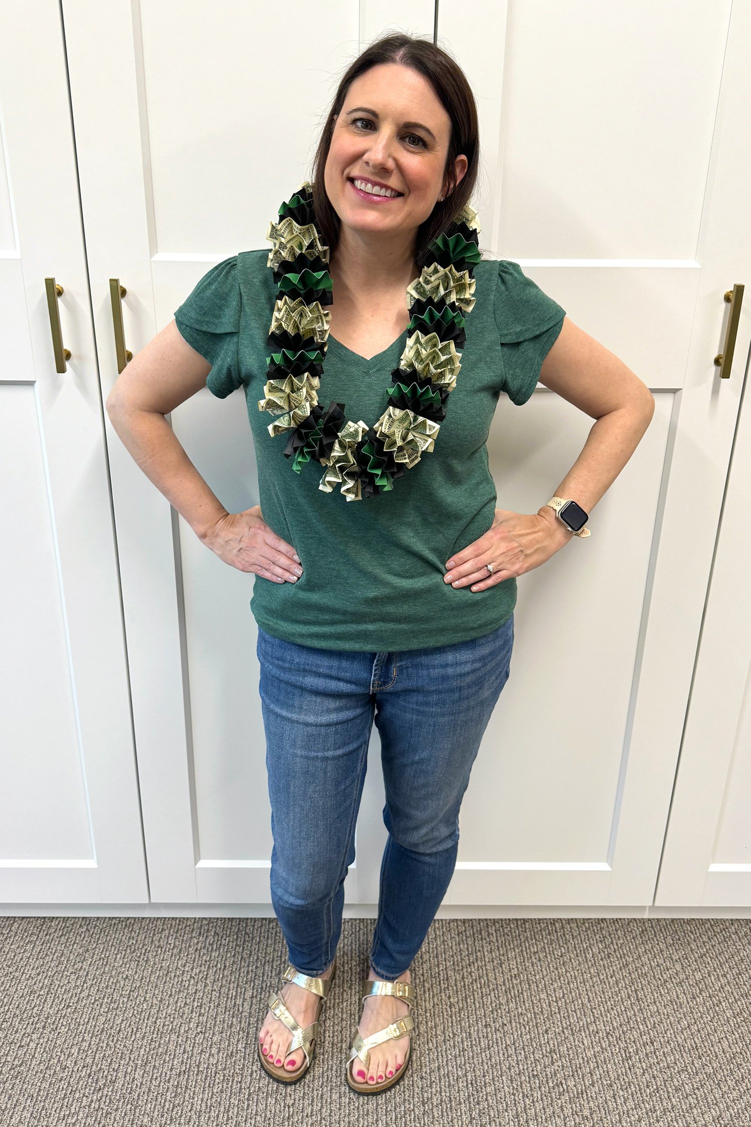 Dark haired woman in green shirt wearing a black and green graduation money lei