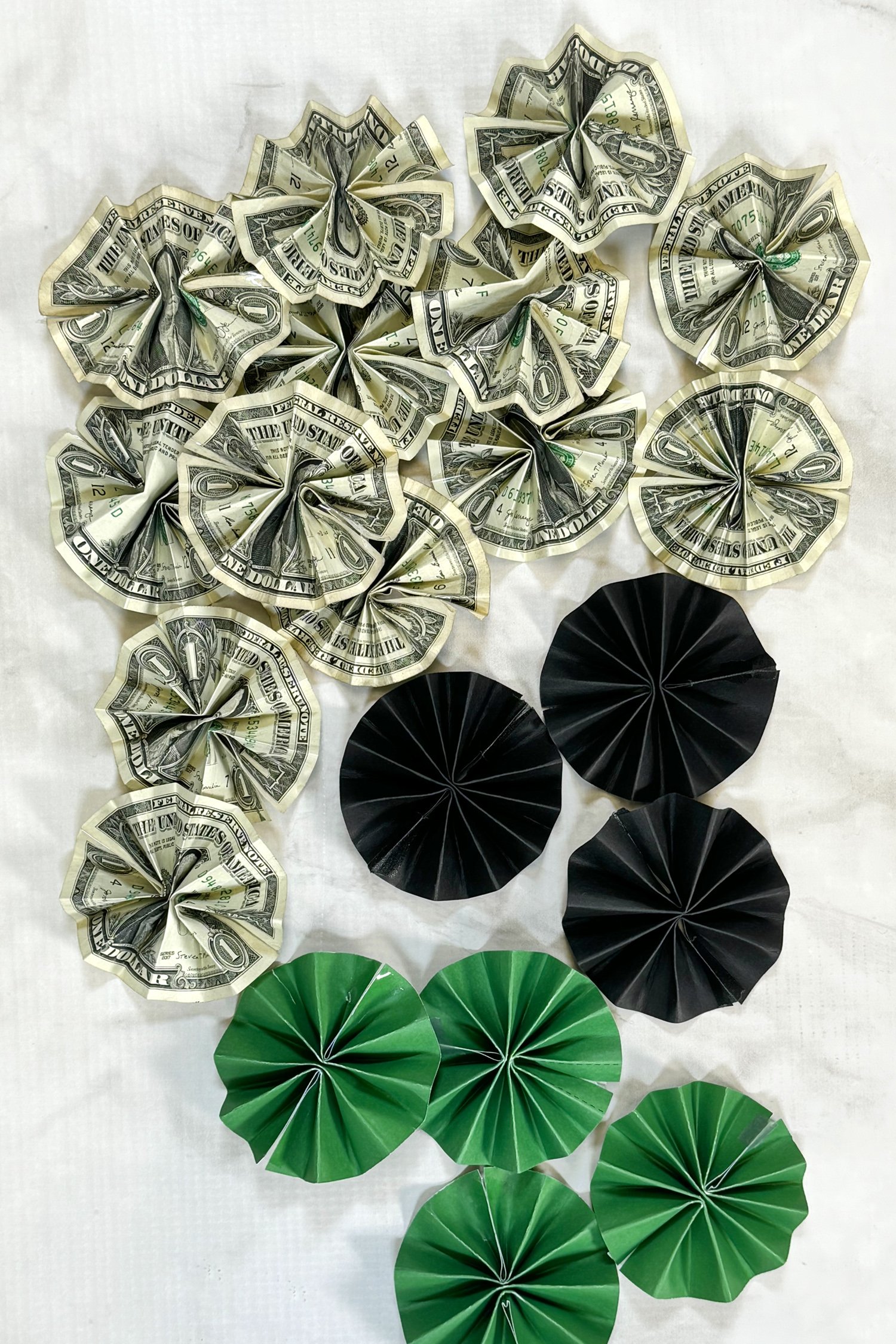 green and black paper rosettes and dollar bill rosettes on grey marble background