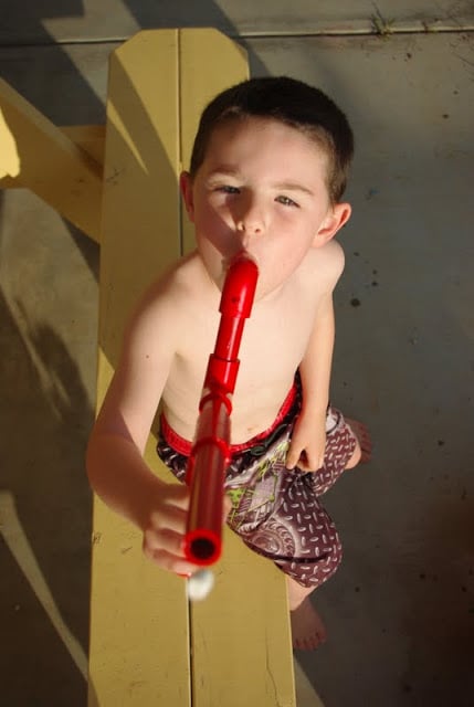 child aiming marshmallow shooter at camera