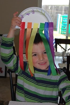 small boy peaking through rainbow streamers