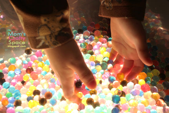 small hands grabbing water beads 