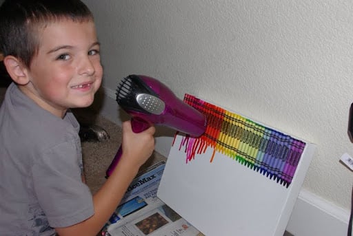 child using blow dryer to melt crayons on canvas