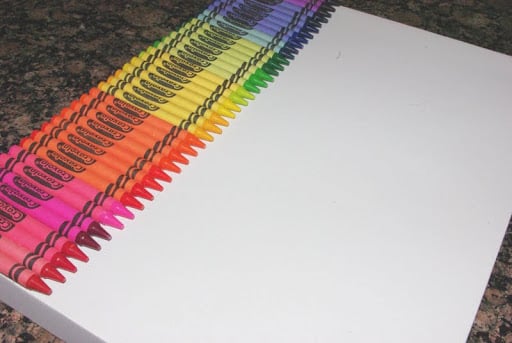 rainbow arrangement of crayons glued to top of white canvas