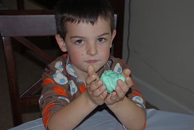 child playing with green slime in hands