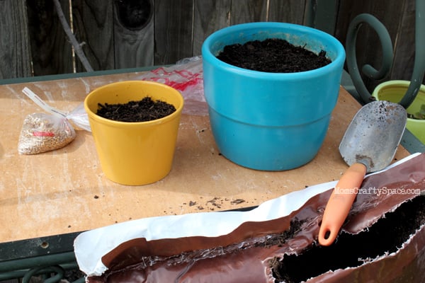 colorful pots being filled with potting soil