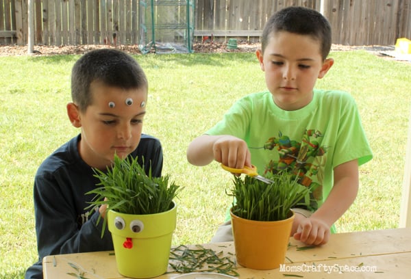 children decorating grass buddies with faces