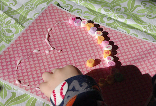 child glueing conversation hearts to paper 