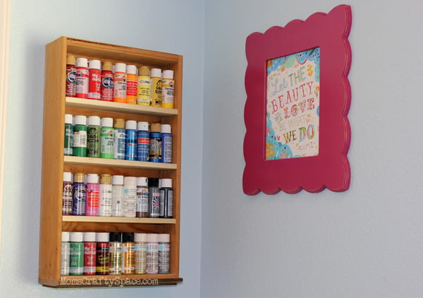 paint storage shelf with assorted paints hanging on wall next to picture