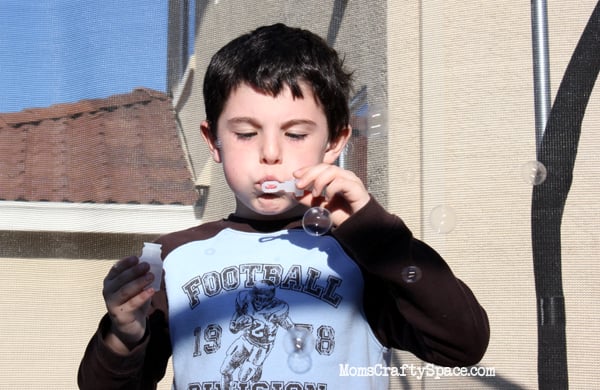 kid blowing bubble outdoors