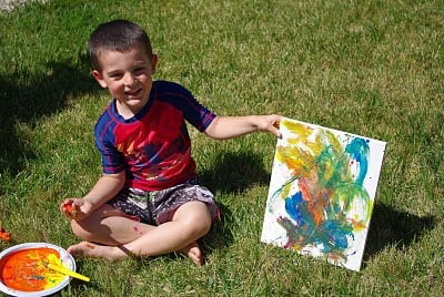 boy proudly holding up kid made painting