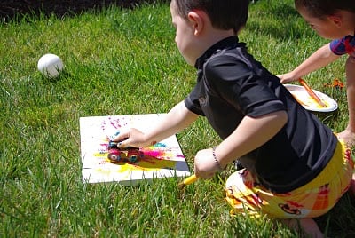 small boy using toy truck to paint