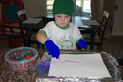 small boy wearing gloves and painting with crayons