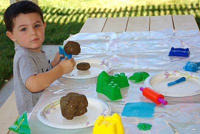 small boy playing with sand mixture and sand tools 