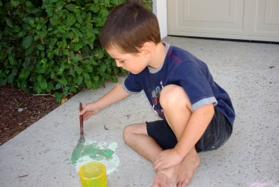 child painting chalk paint on sidewalk