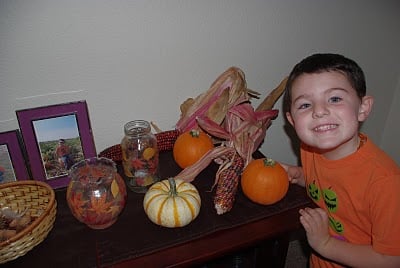 child smiling next to cute fall decor