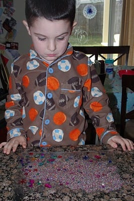 small boy enjoying glitter and sparkles on paper