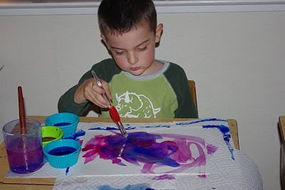 child painting paper with water color paints